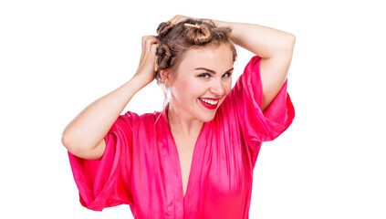 Laughing young woman with curlers on her head. Laughing beautiful blonde in a bright pink bathrobe. Hairstyle and makeup. Isolated on white background.