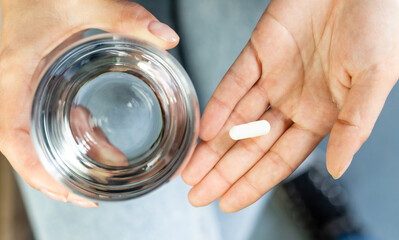 Hands holding tablet and glass with water, responsible use of medication, vitamin supplementation