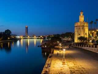Fototapeta na wymiar Vista nocturna del Guadalquivir a su paso por Sevilla, con la Torre del Oro en primer plano