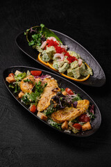Two different kind of salad salad on a black concrete background