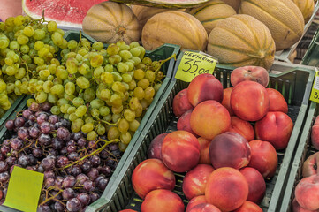 Peaches, grapes, sliced watermelon and ripe melons on the market