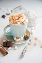 Cappuccino in a blue cup with cinnamon, cream and marshmallows
