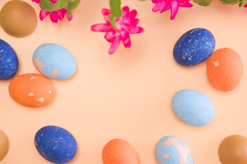 Fototapeta na wymiar Copy space Easter colored eggs on a beige background. Blooming beautiful flower in the frame. mock-up