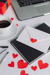 Office desk on Valentine's Day.  Letter, notebook, cup of coffee, laptop, red paper cut out hearts. Flat lay, love concept.
