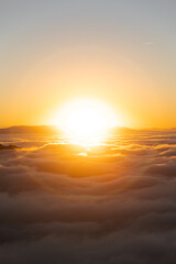 Above the clouds at sunset with a big brilliant sun in the center