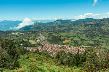 Wide panorama of the colonial village (pueblo) of Jerico (Jericó), Antioquia, Colombia, with a blue sky and the Andes Mountains in the background. From the Cerro las Nubes (Mount of the Clouds).