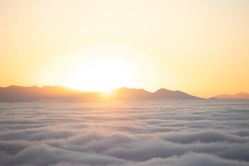 Sea of clouds at sunset with mountains in the background