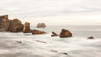 Long exposition of a rocky beach of Arnia in the morning with waves and stones