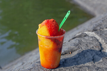 Sweet ice sorbet with mango taste with pepper chili powder and spices - Mexican traditional stret food