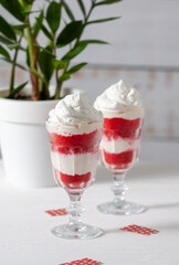 Red velvet cake in glasses with white cream on a white background. A dessert for two lovers for Valentine's Day