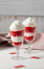 Red velvet cake in glasses with white cream on a white background. A dessert for two lovers for Valentine's Day