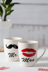 Two white cups that together form a pair. One shows a woman's red lips, and the other a man's black mustache. Good mood for Valentine's Day