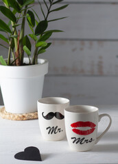 Two white cups that together form a pair. One shows a woman's red lips, and the other a man's black mustache. Good mood for Valentine's Day