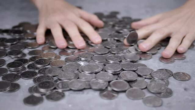Greedy Female Hands are Stirring a Pile of Scattered Ukrainian Coins on Table. A scattering of Ukrainian silver five-kopeck coins. Human greed. Financial crisis, budget savings, money accumulation.