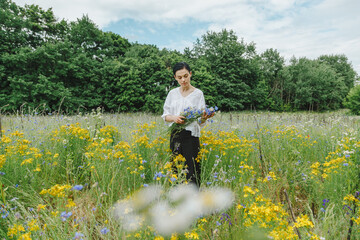 Beautiful girl among the summer field with wildflowers