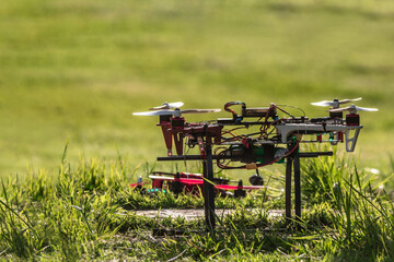 Fototapeta na wymiar Minimalism DIY FPV Drone turning on in grass with blurred background and another drone in the back