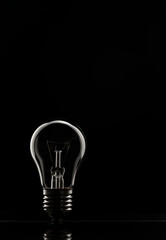 The concept of saving electricity. A tungsten light bulb on a black background.