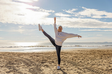 A beautiful energetic young woman doing gymnastics on beach