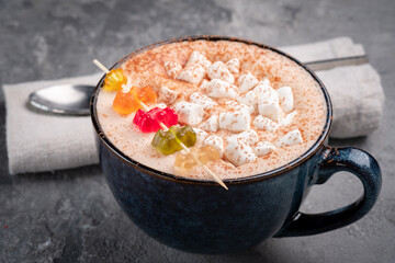 A mug of hot chocolate decorated with marshmallows and jelly candies. Sweet cocoa drink