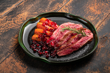 Flank steak fried and chopped on a plate with vegetables and cranberry sauce