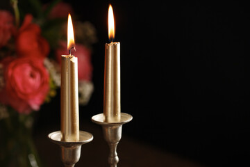 Two burning candles  on dark background. Traditional Jewish Shabbat ritual. Shabbat Shalom.