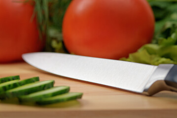 Chopping board with tomato, cucumber, parsley and knife