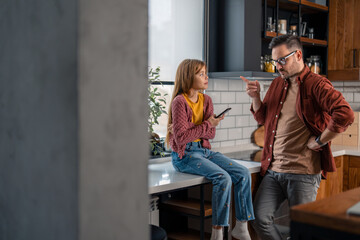 A father and his young daughter discussing her behaviors, setting up new rules at home because she is spending too much time on a smartphone. Family conflict.