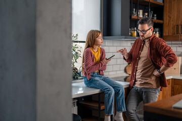 Angry strict father scolding stubborn daughter for spending too much time online on a mobile phone....