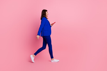 Fototapeta na wymiar Full length profile side photo of adorable cute lady blue stylish suit walk device shop look empty space isolated on pink color background