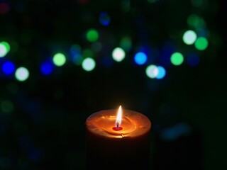 Candle is burning against blurred lights