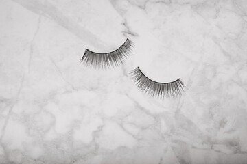 False eyelashes on a white marble background close-up. Makeup. Beauty concept.