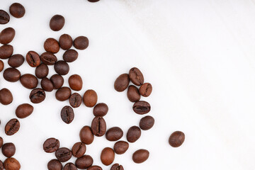 Coffee beans are scattered on a white table. photo of freshly roasted coffee close-up of high quality. top view