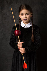A girl with pigtails holds an arrow aimed at an apple
