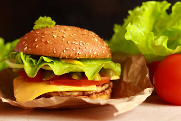 Juicy homemade cheeseburger with fresh lettuce. Fast food closeup. Burger with a sesame seed bun. Selective focus.