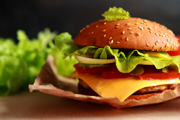 Juicy homemade cheeseburger with fresh lettuce. Fast food closeup. Burger with a sesame seed bun