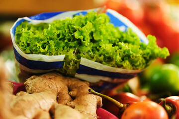 lettuce packed in plastic bags on top of fruits and vegetables at farmers' market