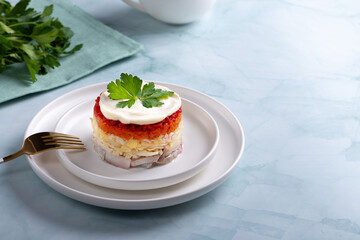Traditional russian salad with herring and vegetables on a green background