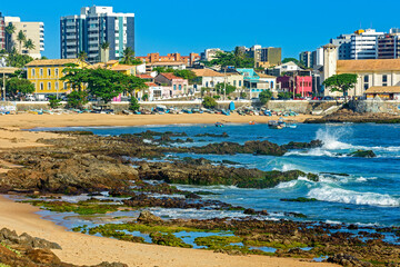 Fototapeta premium Rio Vermelho beach which is known as the bohemian neighborhood of the city of Salvador in Bahia with its rocks, boats and houses on a sunny summer day