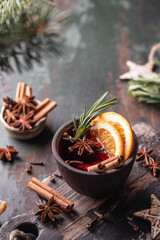 Spiced Mulled wine in ceramic bowl with fruits and rosemary on wooden rustic table, dark key. Traditional hot drink at winter