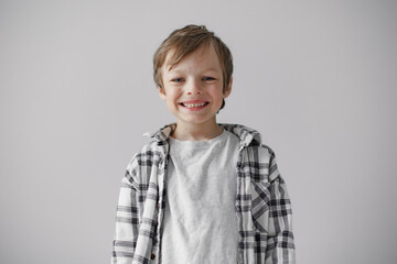 Happy little boy smiling to the camera. Grey studio background.