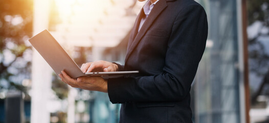Asian business man and young beautiful woman working on digital tablet computer standing outside office building.