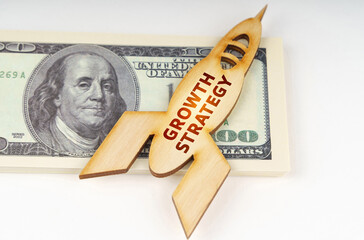 On the dollars lies a wooden model of a rocket with the inscription - Growth Strategy