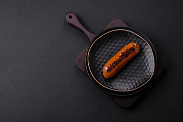 Delicious fresh eclair with chocolate cream on a black ceramic plate