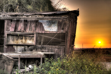 Abandoned old wooden shack in front of beautiful sunset