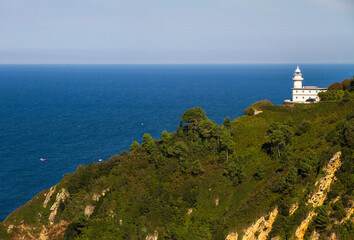 Fototapeta na wymiar Lighthouse on Mountainside in spain, with blue sea background