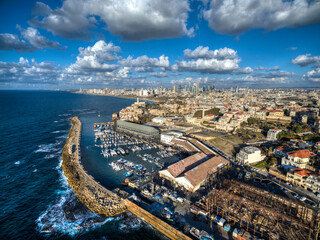 Obraz premium Aerial view of Ships anchoring at the Jaffa port in a cloudy day. tel aviv skyline with urban skyscrapers at the background