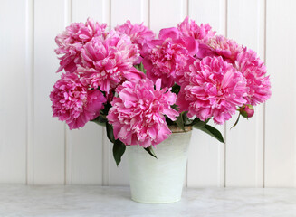 pink peonies in a decorative bucket on a table. garden flowers.