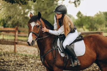 A young female jockey is sitting on her horse in show jumping training. Preparing for the...