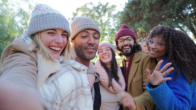 Group of young people smiling and having fun taking selfie portrait. Five multiracial happy friends looking at camera. Funny outdoor activity of cheerful students away from home. Lifetyle concept