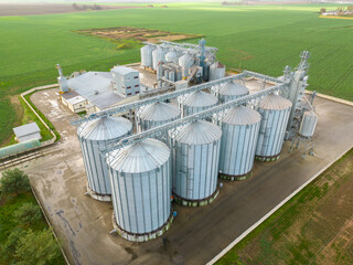 silver silos on agro manufacturing plant for processing drying cleaning and storage of agricultural products, flour, cereals and grain. Flying a drone over iron barrels of grain. quadcopter photo © Pokoman